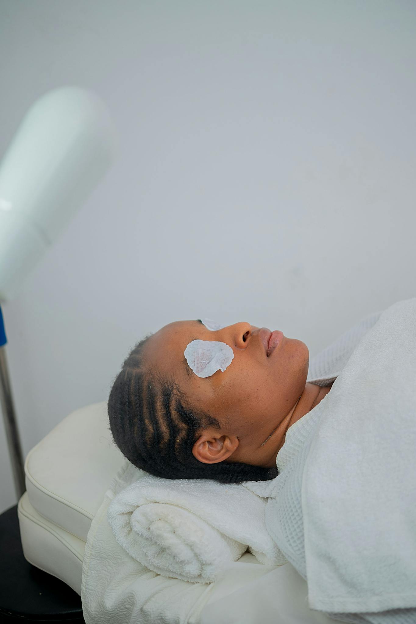 A serene facial spa experience in Abuja with a woman resting under a towel.